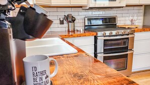 Een keuken met witte kastjes, een magnetron, een oven en een koffiezetapparaat op het aanrecht.
