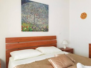Ein Hotelzimmer mit einem hölzernen Bett, weißer Bettwäsche, einem Nachttisch mit Lampe und einem Bild an der Wand.