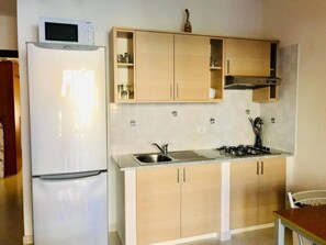 A kitchen with a refrigerator, sink, stove, and wooden cabinets. - Pizzo Beach Club One Bedroom Apartment 128G (PIZZO)