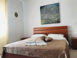 A neatly made bed with a brown headboard, white pillows, and a striped blanket. - Pizzo Beach Club One Bedroom Apartment 128G (PIZZO)