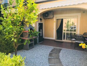 Une terrasse avec un barbecue, une porte et un espace salon avec des chaises.