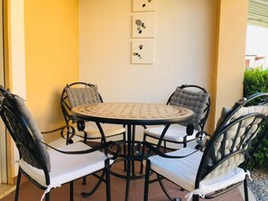 A round table with four chairs, a tiled floor, and a wall with three framed artworks. - Pizzo Beach Club One Bedroom Apartment 128G (PIZZO)