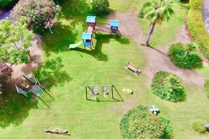 An aerial view of a park with playground equipment, a bench, and landscaped areas.