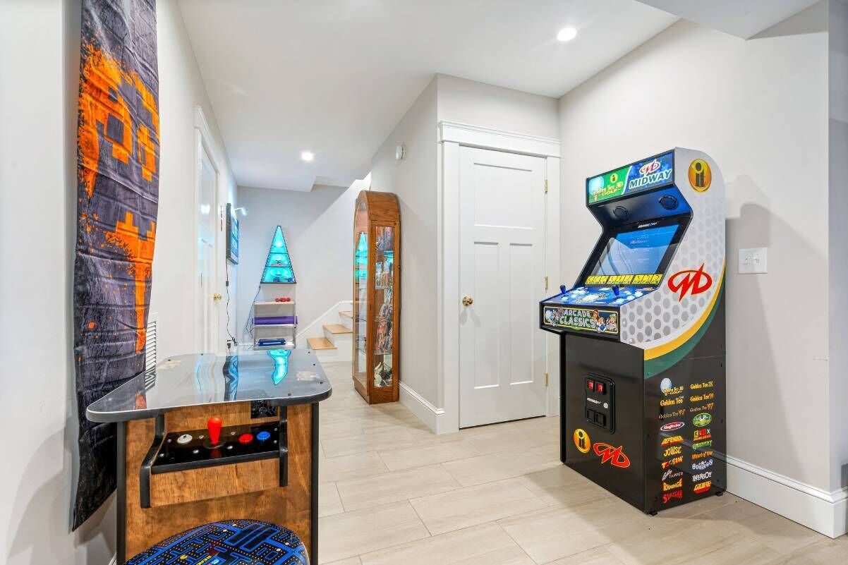 A hallway with a gaming console, a small table with a chair, and a door.