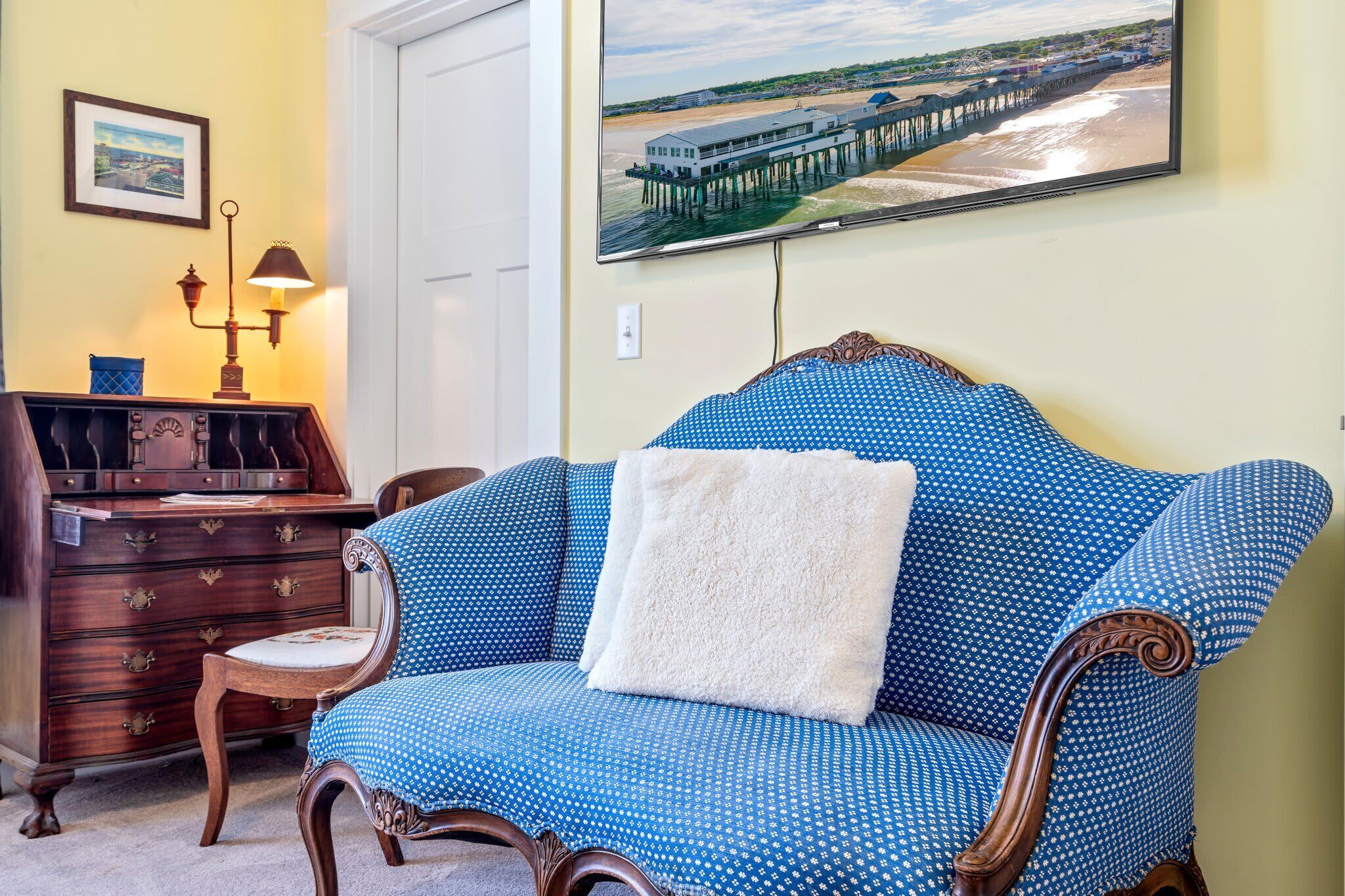 Une pièce avec un canapé bleu à motifs, une commode en bois et un tableau encadré accroché au mur.