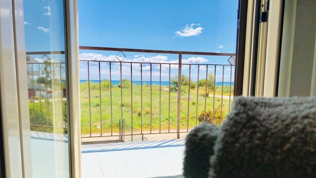 Ein Balkon mit Metallgeländer, Blick auf eine grüne Landschaft und eine Tischdecke mit Blumenmuster.