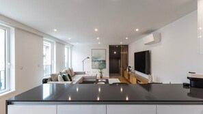 A modern kitchen with a large island, a dining area with a sofa, and a TV mounted on the wall. - Morro Premium Apartment w/ Free Parking (Vila Nova de Gaia)
