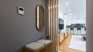 A modern interior with a wooden bench, a wall-mounted mirror, and a kitchen area visible through an open door. - Morro Premium Apartment w/ Free Parking (Vila Nova de Gaia)
