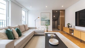 A modern living room with a sofa, a coffee table, and a TV. - Morro Premium Apartment w/ Free Parking (Vila Nova de Gaia)