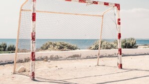 Una estructura de postes de fútbol en la playa, con una vista despejada del mar al fondo.