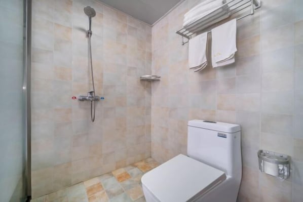 Une salle de bain équipée de toilettes, d’une douche et d’un porte-serviettes.