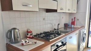 Una cocina moderna con estufa a gas, hervidor, microondas y lavadora.