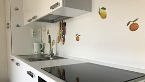 Een keuken met een zwart inductiekookveld, witte kastjes en een vaatwasser.