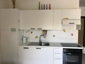 Una cocina compacta con armarios blancos, lavavajillas integrado y estufa.
