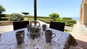 Ein Tisch im Freien mit Meerblick, umgeben von Stühlen und einem Wasserkocher.