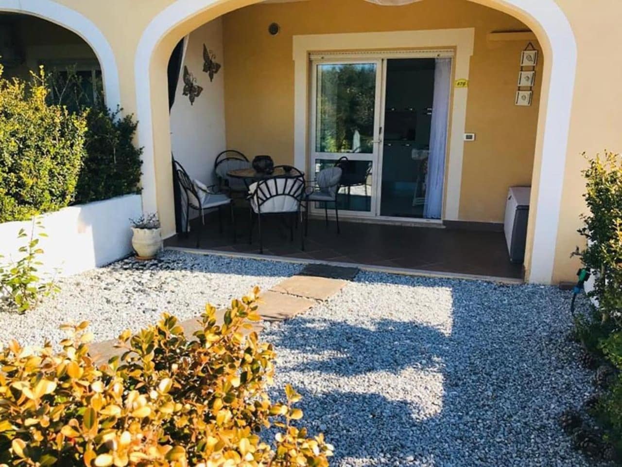 Un patio couvert avec une table et des chaises, une porte-fenêtre coulissante et un sol en gravier.