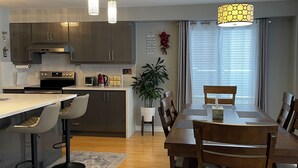 Una cucina moderna con elettrodomestici in acciaio inossidabile, un'area pranzo con mobili in legno e un'ampia finestra con tende.