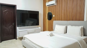 Une chambre d’hôtel équipée d’un lit, d’une télévision, d’un mur recouvert de panneaux en bois et d’un appareil de climatisation.