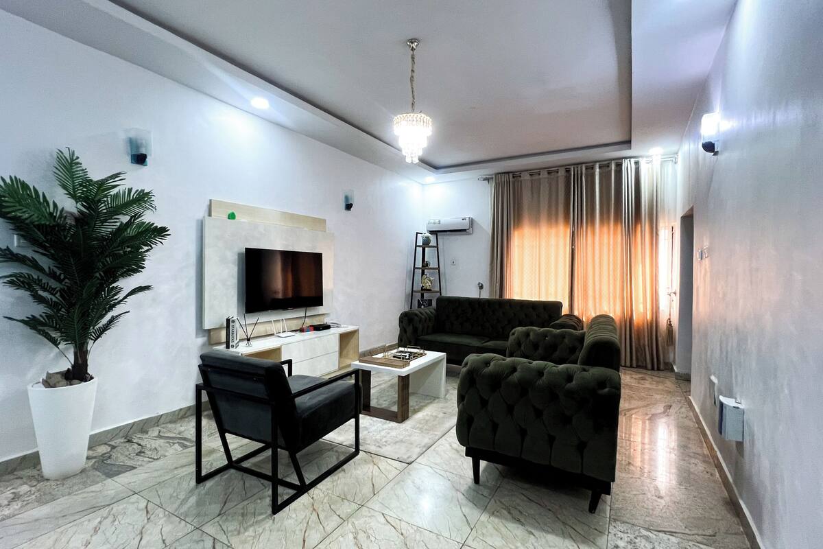 A living room with a flat-screen TV, a sofa, a coffee table, and a potted plant.