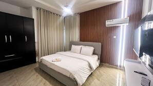 Een hotelkamer met een bed, een kledingkast, een airconditioner en een bureau met een afstandsbediening.