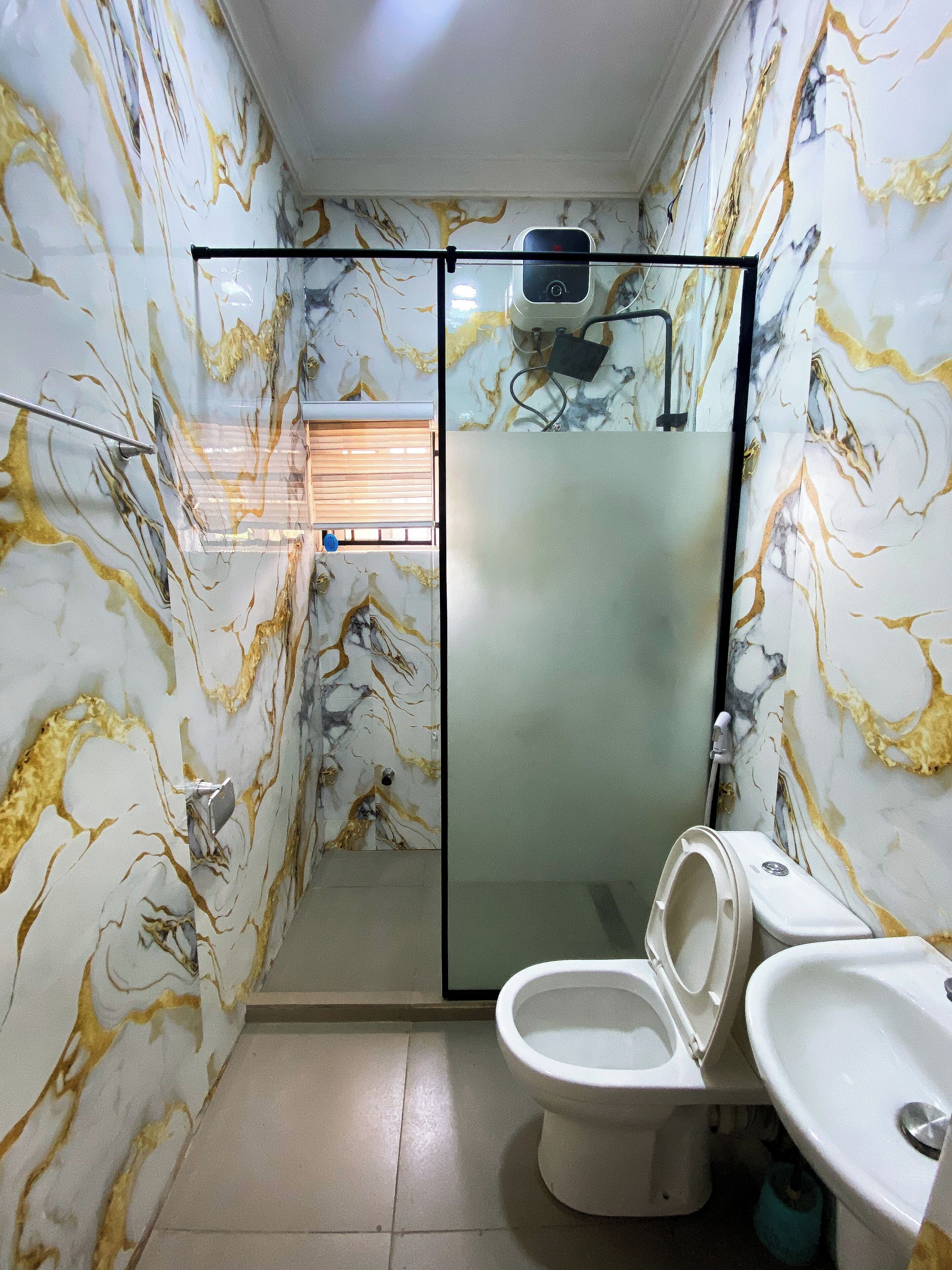 A bathroom with a glass-enclosed shower, a toilet, and a sink.