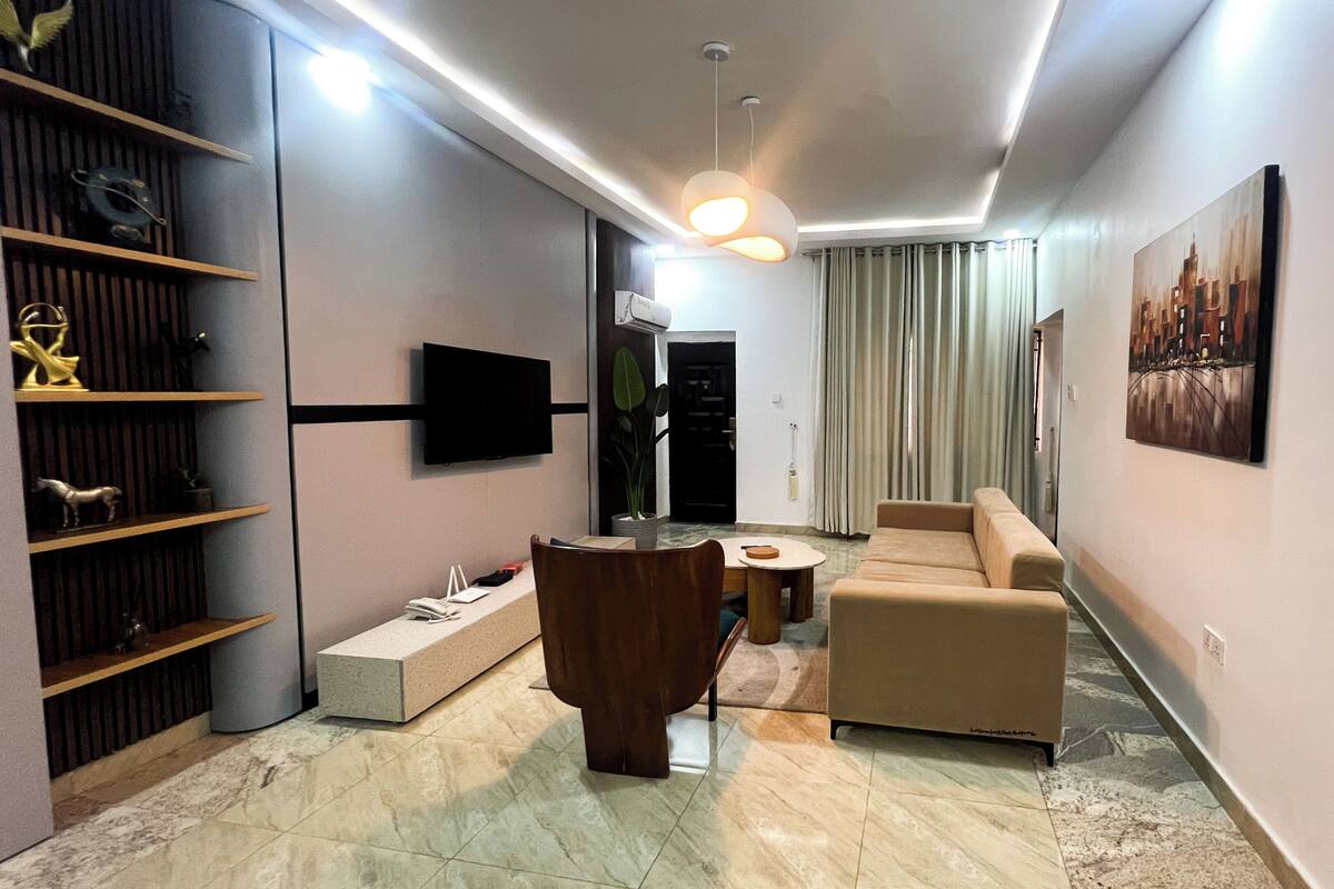 A modern living room with a sofa, a coffee table, a TV, and a bookshelf.