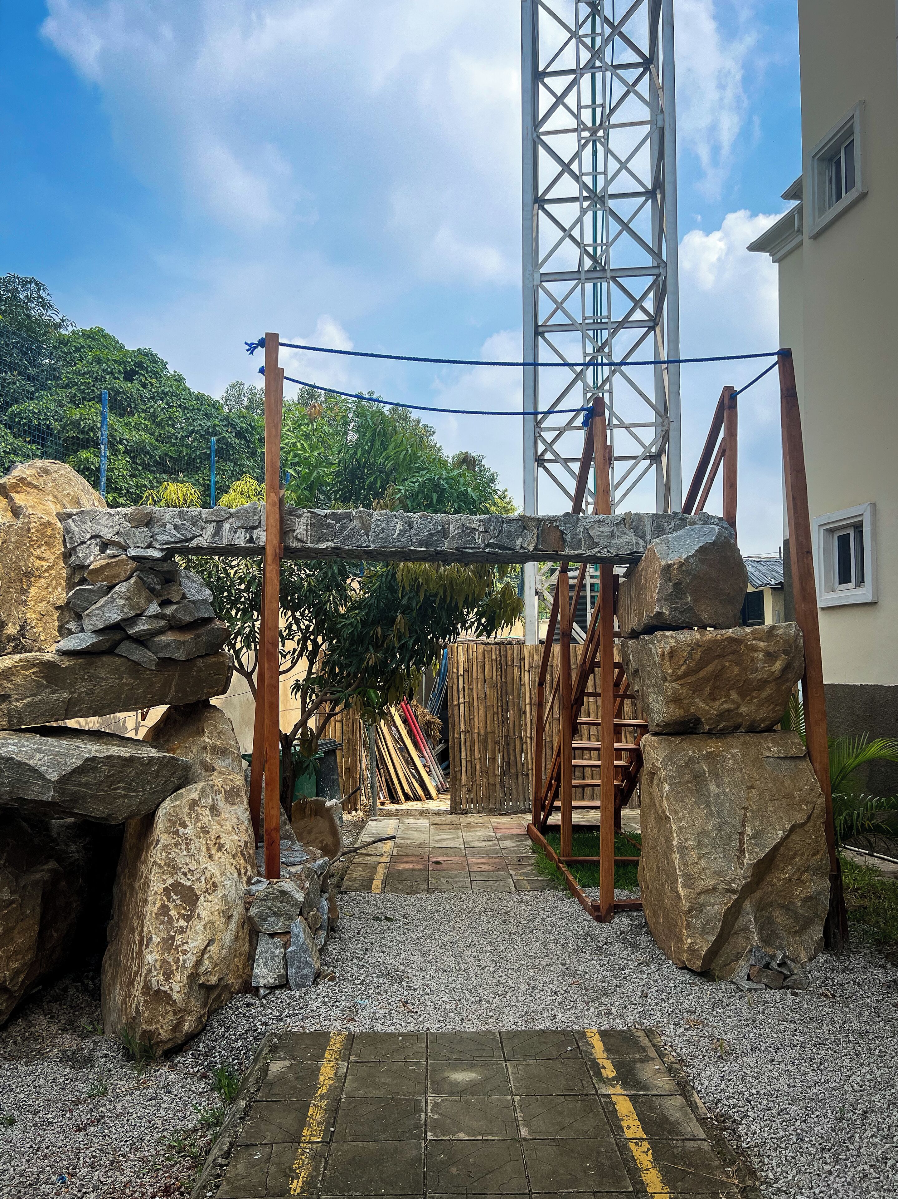 A construction site with large rocks, a metal structure, and a building in the background.