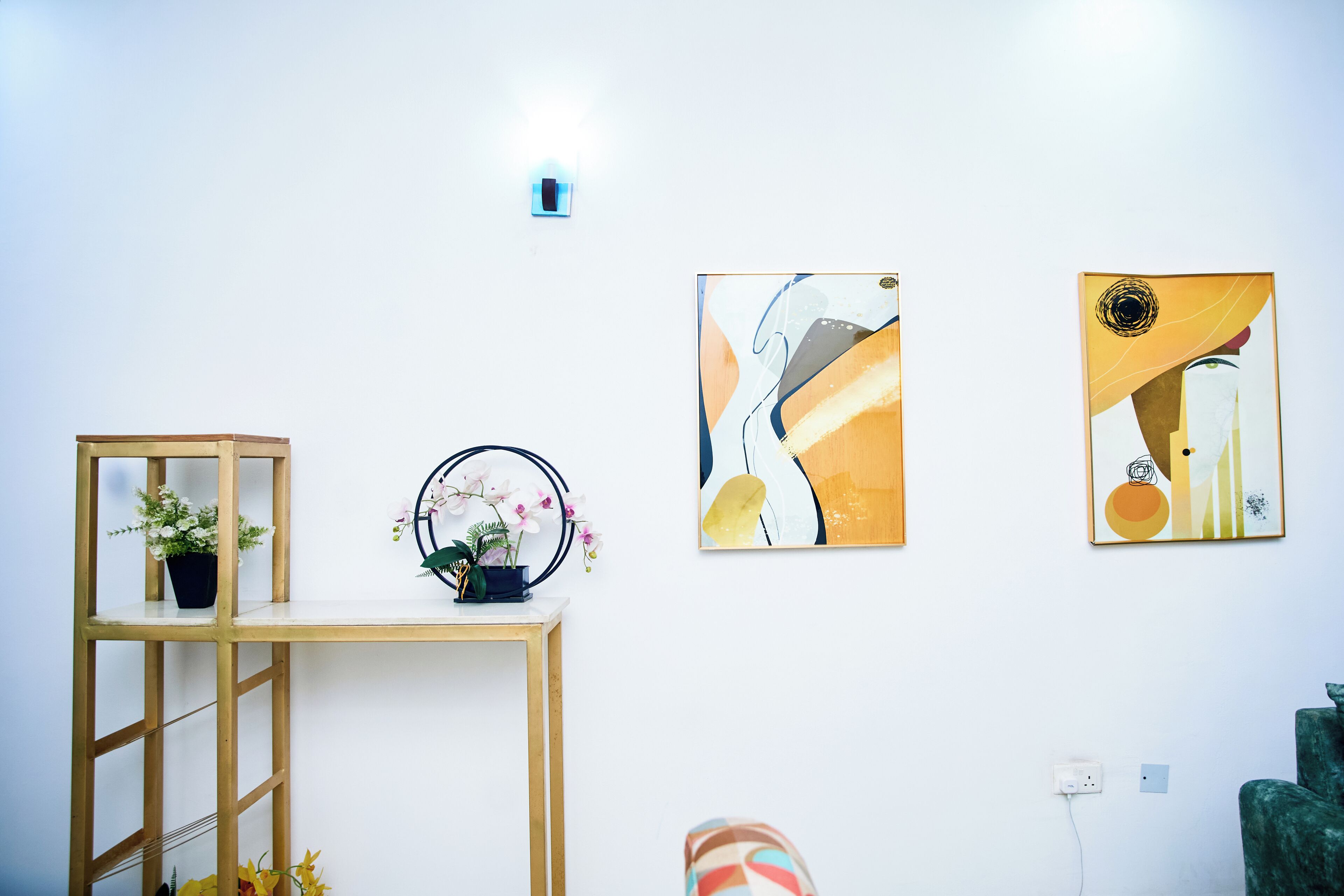 Una habitación con una consola de madera, una planta en maceta y dos cuadros abstractos en la pared.
