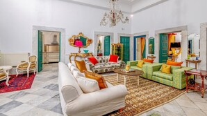 A spacious living room with a chandelier, green doors, and a variety of seating options including a sofa and armchairs. - La Demeure Médina (Tunis)