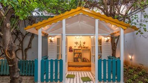 A cozy, enclosed outdoor space with a white and yellow roof, a small seating area with a bench, and a bookshelf filled with books and decorative items. - La Demeure Médina (Tunis)