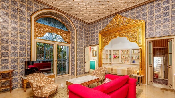 A spacious living room with a red sofa, patterned armchairs, a marble coffee table, and a bookshelf. - La Demeure Médina (Tunis)