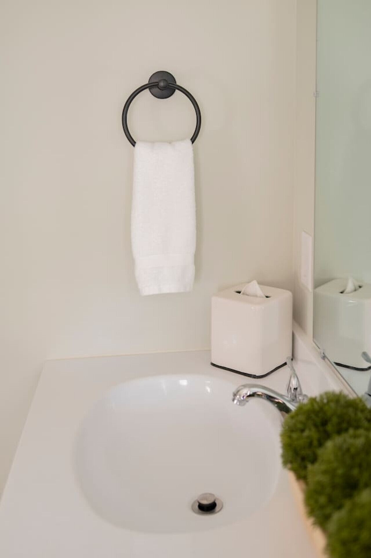 Une salle de bain avec un lavabo blanc, un porte-serviettes et un boîte à mouchoirs.