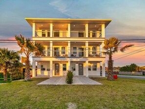 Un edificio residenziale a più piani con tetto piatto, un ingresso centrale e una strada privata che conduce all'ingresso.