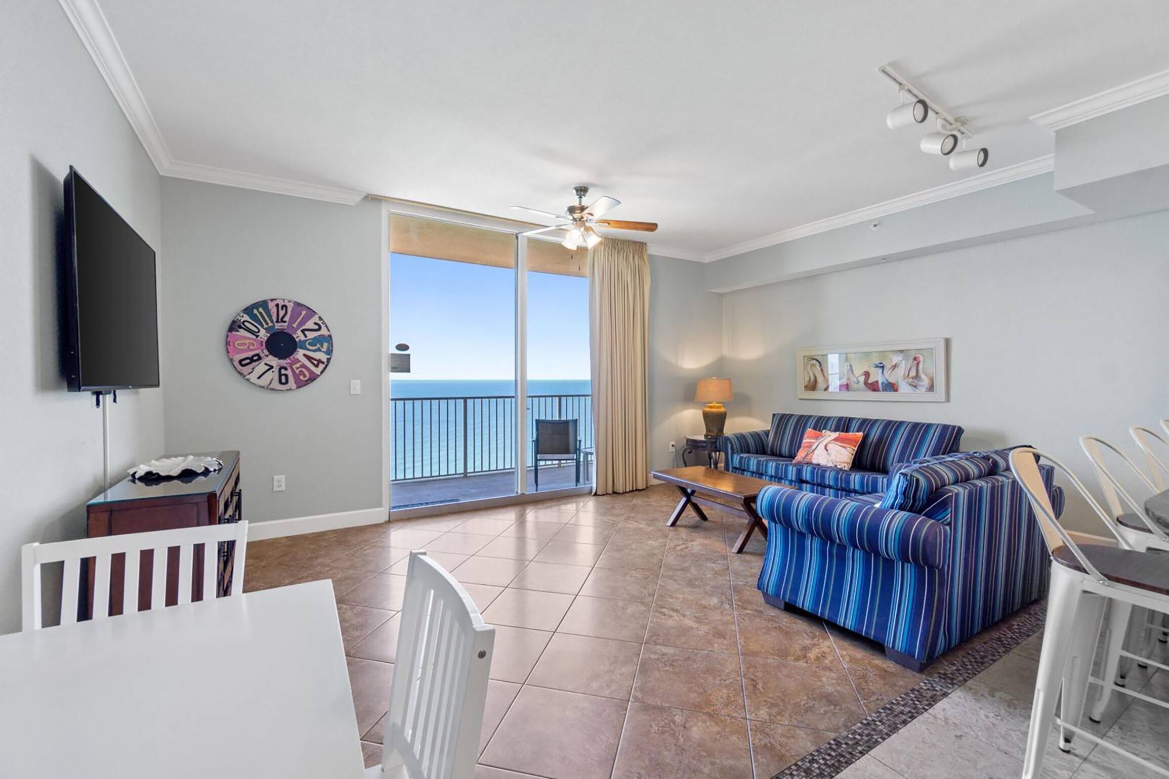 A living room with a sofa, TV, and a view of the ocean.