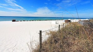 A sandy beach with a wooden fence and a clear blue sky.
