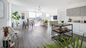 A modern living room with a dining area, a kitchen, and a view of the city. - Stylish London Flat - Private Terrace - City View (London)