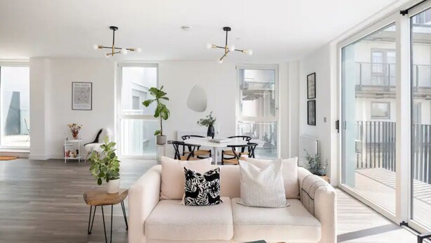 A modern living room with a sofa, a coffee table, and a dining area with a table and chairs. - Stylish London Flat - Private Terrace - City View (London)