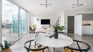 A modern living room with a round white table, black chairs, and a large window offering a city view. - Stylish London Flat - Private Terrace - City View (London)