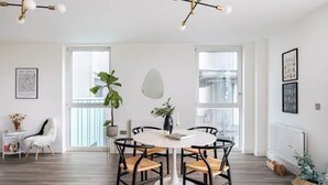 A modern dining area with a round table, black chairs, and a potted plant. - Stylish London Flat - Private Terrace - City View (London)