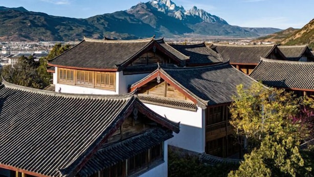 Traditional buildings with tiled roofs and wooden structures, set against a mountainous backdrop. - Mulan Villa (Lijiang)