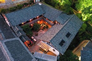 A traditional courtyard with a central seating area, surrounded by buildings with sloped roofs. - Mulan Villa (Lijiang)