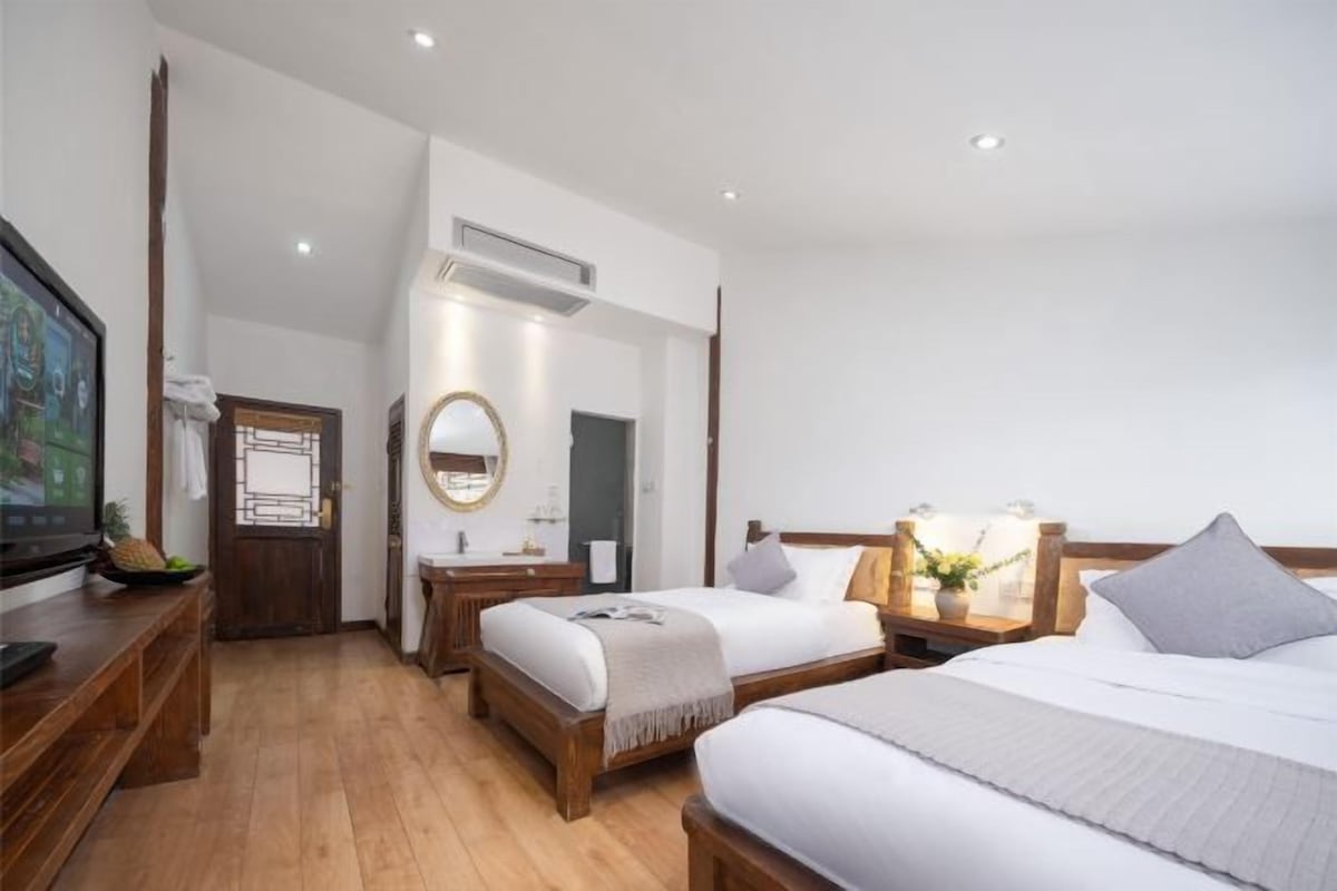 A hotel room with a bed, bedside tables, a TV, and a bathroom.