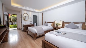 Ein modernes Hotelzimmer mit zwei Betten, einem Holztisch, einem runden Spiegel und Blick ins Freie.