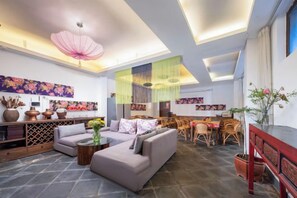 A spacious living area with a sofa set, a dining table, and a decorative ceiling. - Mulan Villa (Lijiang)