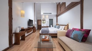A modern hotel room with a large bed, a sofa, a glass coffee table, a TV, and wooden furniture. - Mulan Villa (Lijiang)