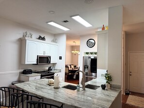 Enjoy cooking in this well-lit kitchen with a central island, microwave, and stainless steel refrigerator.