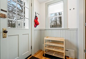 A room with a wooden bench, a door with a keyhole, and a window with a view of trees.
