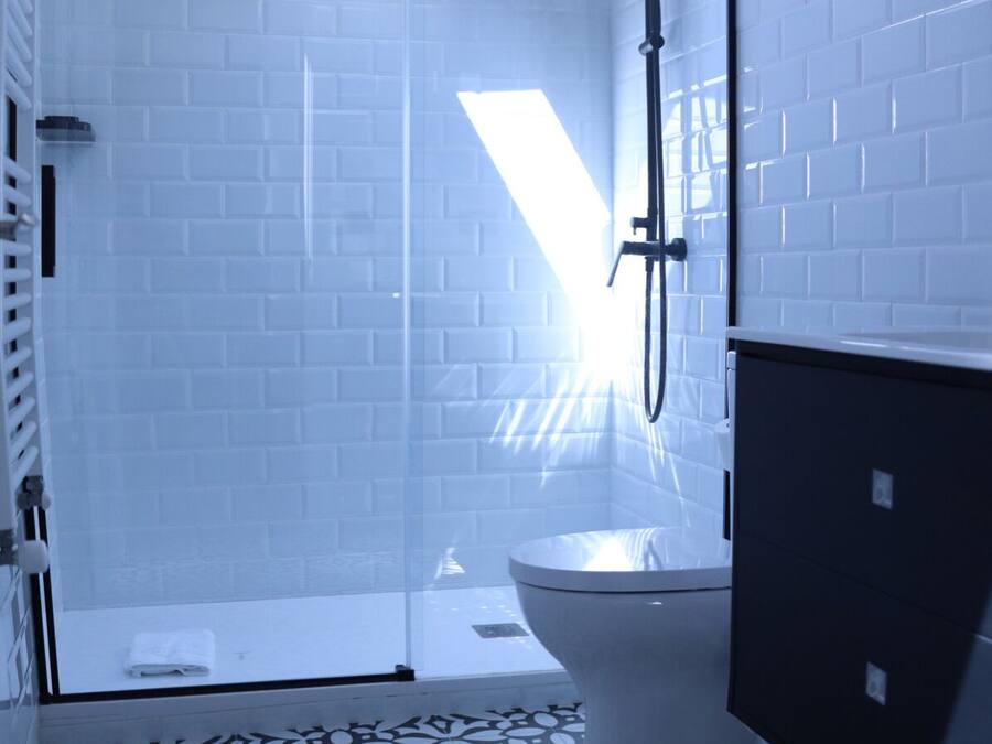 A modern bathroom with a glass shower enclosure, a toilet, and a sink.