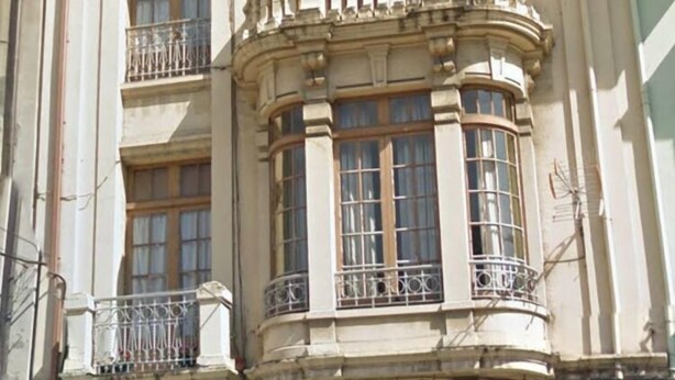 Un edificio de varias plantas con arquitectura clásica, que presenta ventanas de arco y balcones.