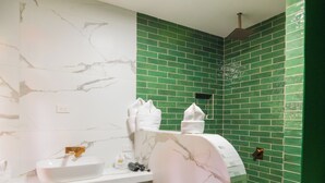 A bathroom with a white marble vanity, a green-tiled shower area, and a white bathtub.